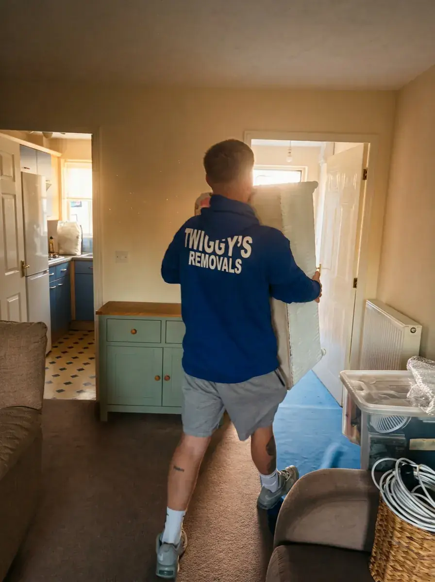 A Twiggy’s crew member carrying furniture through a living room, with the floor protected