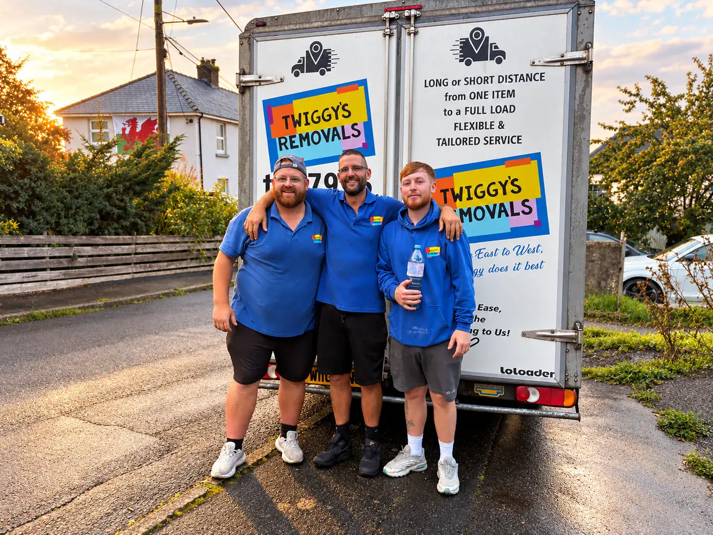 Three of the Twiggy’s Removals crew in their blue uniforms, standing together at the back of the van